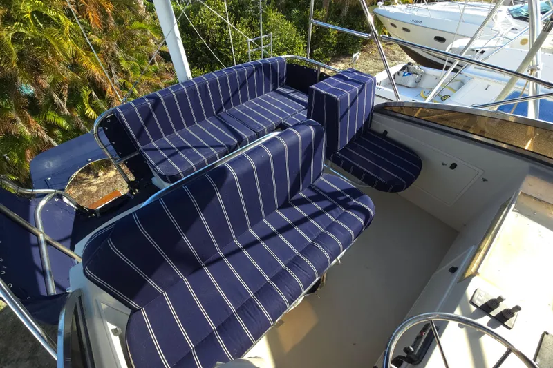 Slide: The Image of 2004 Legacy Yachts Sedan Flybridge with striped seating, docked near lush greenery. - 20
