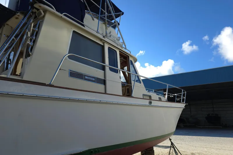 Slide: The Image of 2004 Legacy Yachts Sedan Flybridge in a boatyard under a clear blue sky. - 24