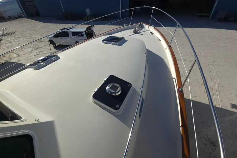 Slide: The Image of 2004 Legacy Yachts Sedan Flybridge deck with railing, parked near a white vehicle. - 25