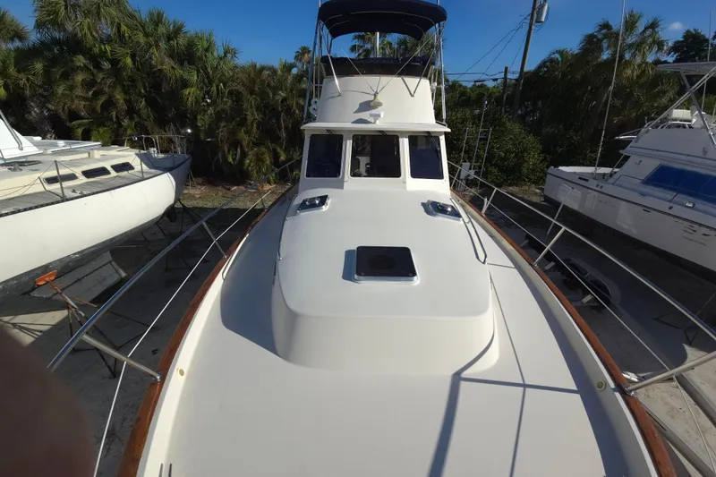 Slide: The Image of 2004 Legacy Yachts Sedan Flybridge on land, surrounded by trees and other boats. - 27