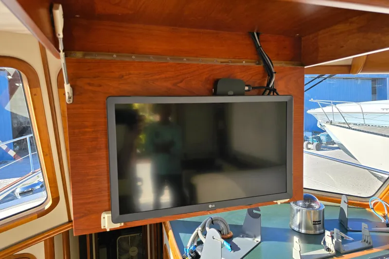 Slide: The Image of 2004 Legacy Yachts Sedan Flybridge interior with mounted LG TV and nautical equipment. - 7