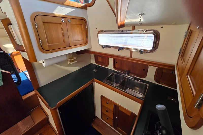 Slide: The Image of 2004 Legacy Yachts Sedan Flybridge kitchen with wooden cabinets and dual sink. - 9