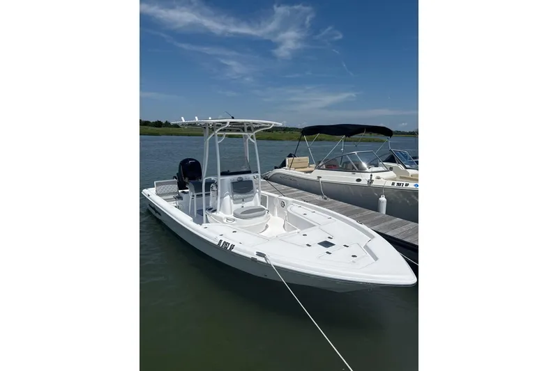 Slide: The Image of 2025 NauticStar 214 Shallow Bay boat docked on calm water under clear sky. - 3