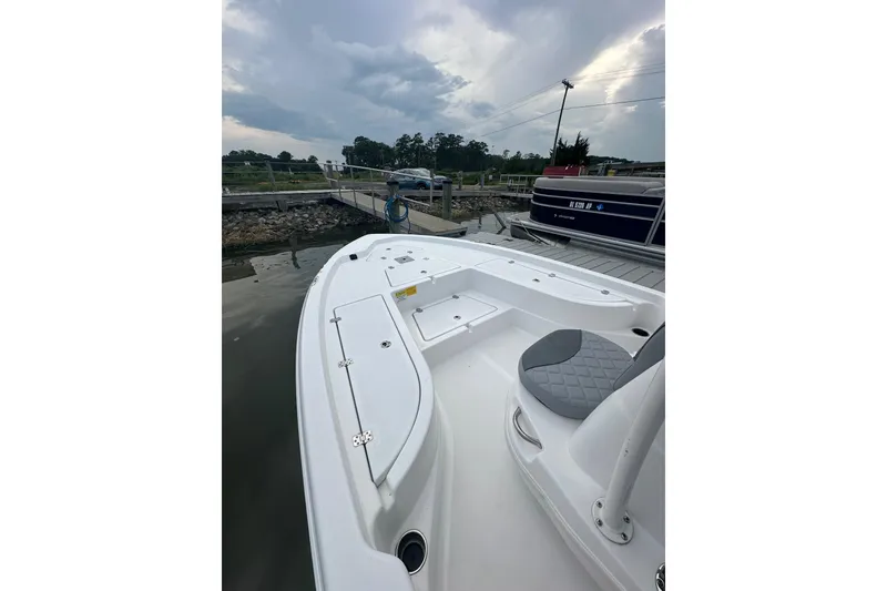 Slide: The Image of 2025 NauticStar 214 Shallow Bay boat docked, showcasing spacious deck and seating. - 3