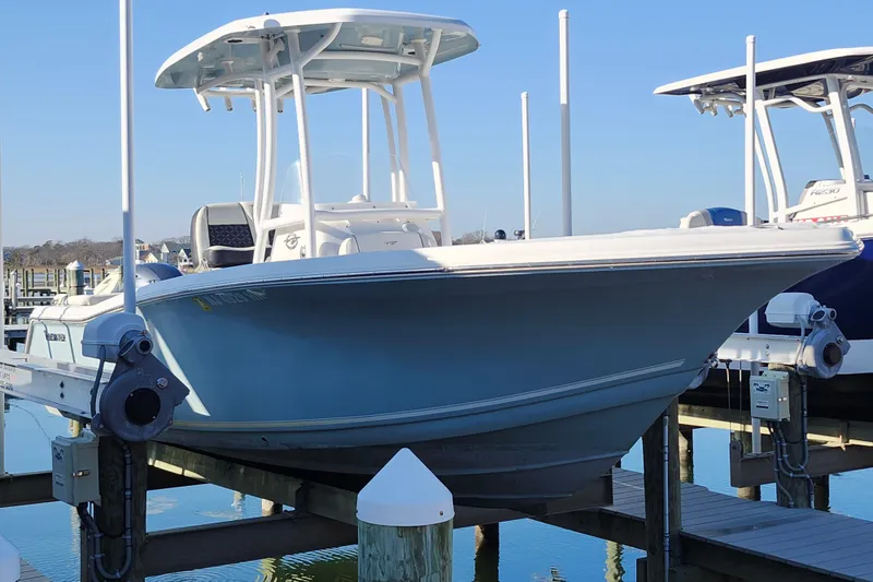 Slide: The Image of 2022 Tidewater 220 LXF boat docked at marina, clear blue sky background. - 1