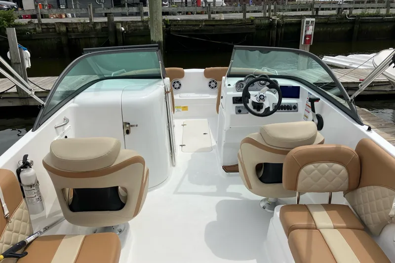 Slide: The Image of 2025 NauticStar 223 DC Deck boat interior with beige seating and modern dashboard. - 5