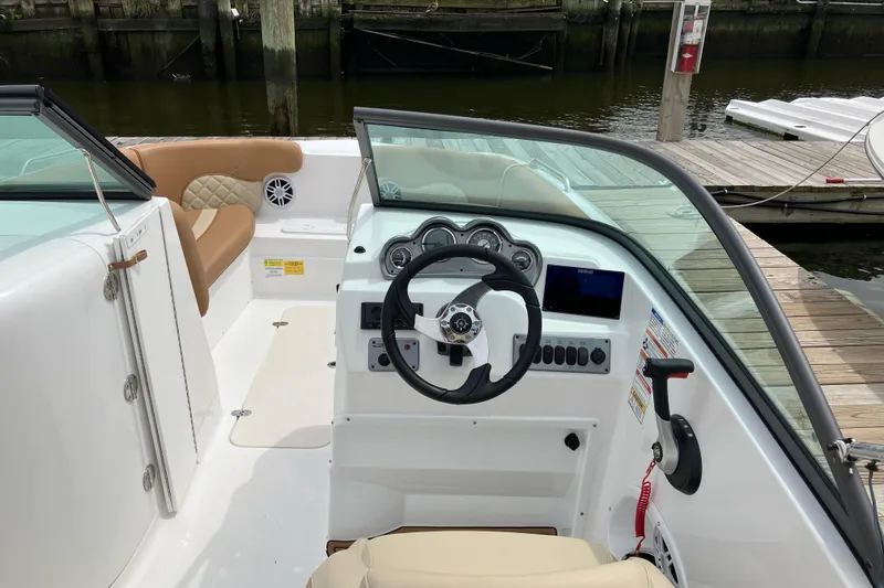 Slide: The Image of 2025 NauticStar 223 DC Deck boat interior with steering wheel and dashboard at dock. - 6