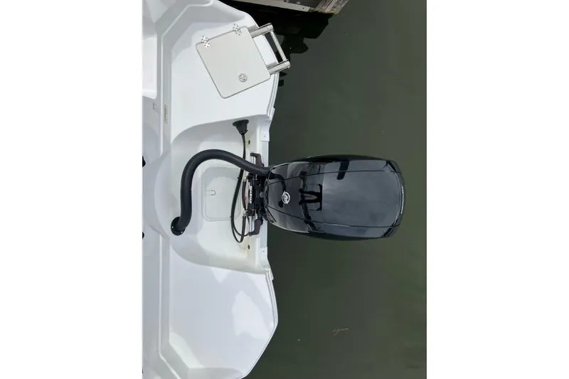 Slide: The Image of 2025 NauticStar 223 DC Deck boat with outboard motor, docked on calm water. - 7
