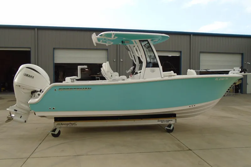Slide: The Image of 2024 Sportsman Heritage 231 Center Console boat in turquoise, parked outside a warehouse. - 4