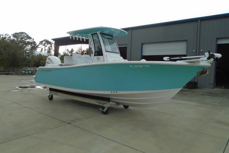 Slide: The Image of 2024 Sportsman Heritage 231 Center Console boat in turquoise, parked outside a warehouse. - 5