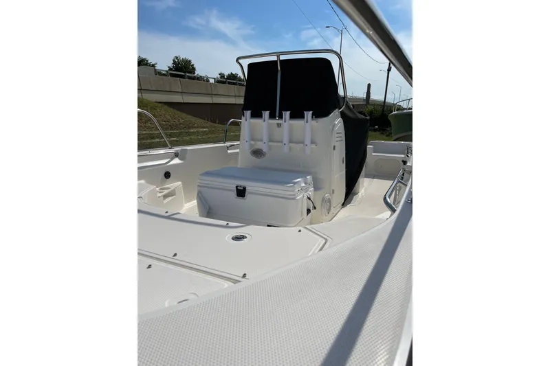 Slide: The Image of 2022 Boston Whaler 170 Montauk boat interior with seating and storage, under clear blue sky. - 2