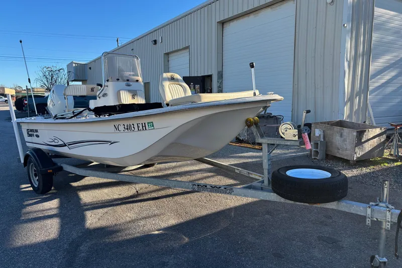 The Image of 2018 Carolina Skiff 18 JVX CC boat on trailer outside a warehouse. - 1