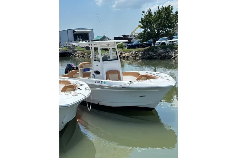 Slide: The Image of 2025 NauticStar 242L Offshore boat docked in a marina under a clear sky. - 2