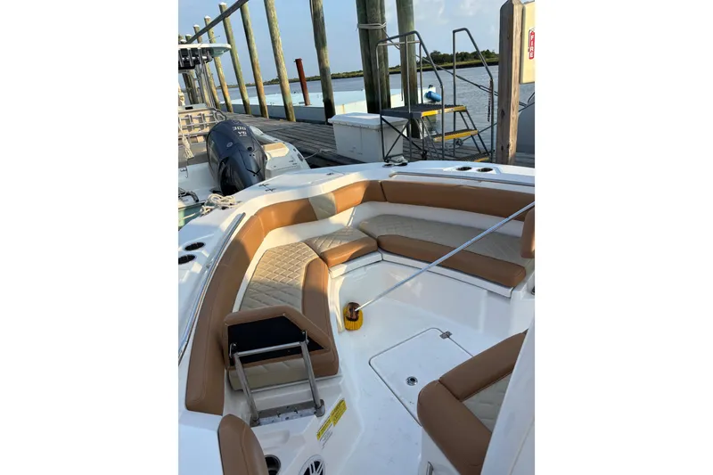 Slide: The Image of 2025 NauticStar 242L Offshore boat interior with tan seating at dock. - 4