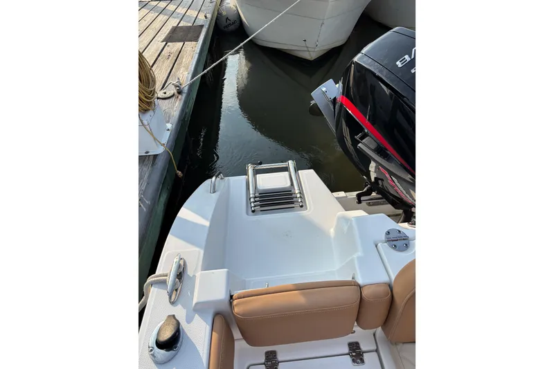 Slide: The Image of 2025 NauticStar 242L Offshore boat stern view with motor and dock. - 7