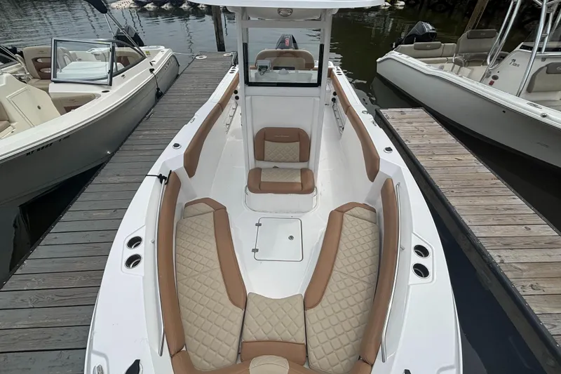 Slide: The Image of 2025 NauticStar 242L Offshore boat with tan seating, docked at marina. - 5