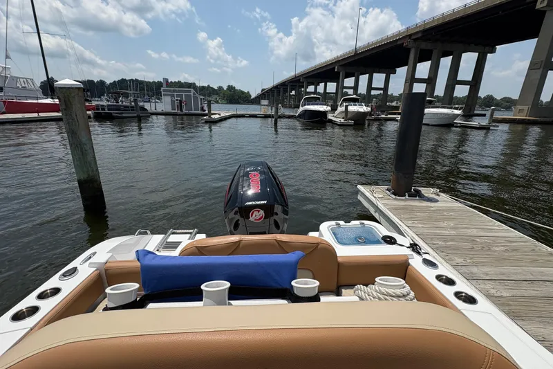Slide: The Image of 2025 NauticStar 242L Offshore boat docked near a bridge on a sunny day. - 7