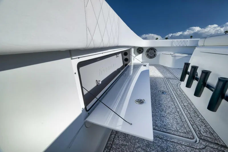Slide: The Image of 2023 Freeman 43 boat interior with storage compartment and rod holders, under a clear blue sky. - 24