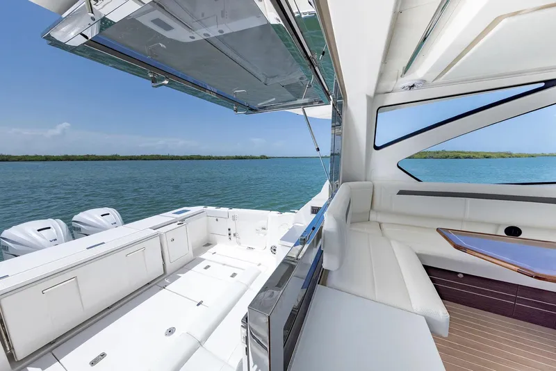 Slide: The Image of Manufacturer Provided Image: 2025 Pursuit OS 445 Offshore yacht interior with ocean view, featuring luxurious seating and modern design. - 13