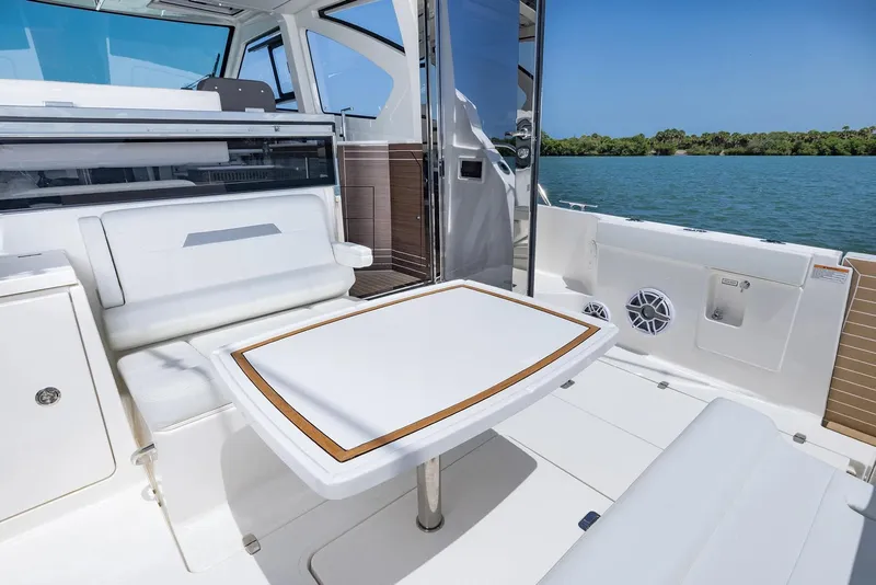 Slide: The Image of Manufacturer Provided Image: 2025 Pursuit OS 445 Offshore boat interior with seating and table, overlooking serene water. - 14