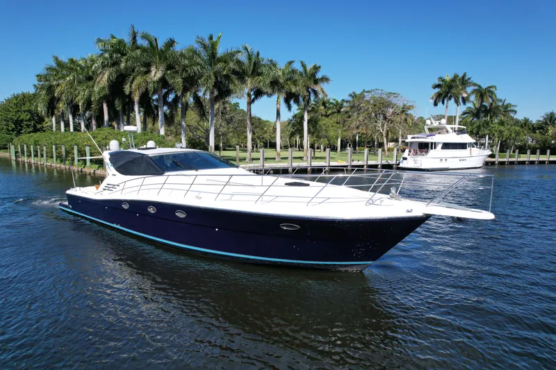 Slide: The Image of 1999 Uniesse 57 Open yacht cruising on a sunny day with palm trees in the background. - 6