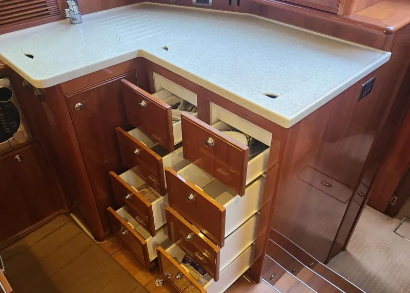 Slide: The Image of 2009 Riviera 47 Enclosed Flybridge Series II yacht kitchen with open wooden drawers. - 19
