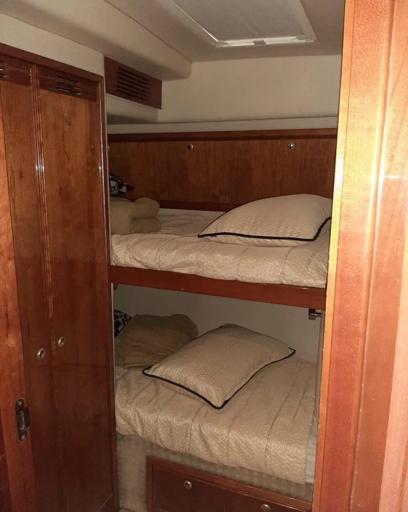 Slide: The Image of 2009 Riviera 47 Enclosed Flybridge Series II cabin with wooden bunk beds and storage. - 28