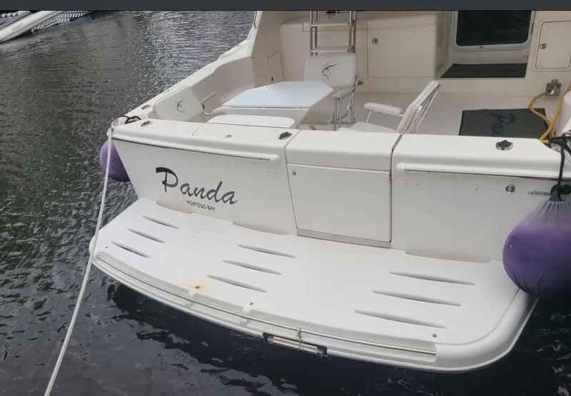 Slide: The Image of 2009 Riviera 47 Enclosed Flybridge Series II boat docked, featuring "Panda" name on the stern. - 54