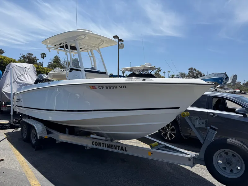 Slide: The Image of 2019 Boston Whaler 230 Outrage boat on trailer, parked outdoors under clear sky. - 4