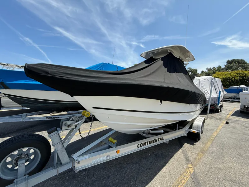 Slide: The Image of 2019 Boston Whaler 230 Outrage boat covered on a Continental trailer in a parking lot. - 42