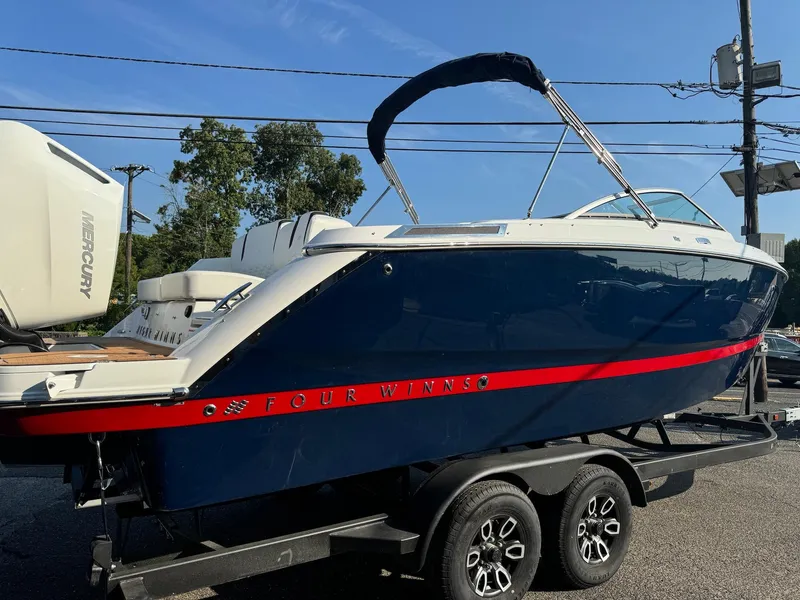 Slide: The Image of 2025 Four Winns H6 OB boat on trailer, blue with red stripe, outdoor display. - 2