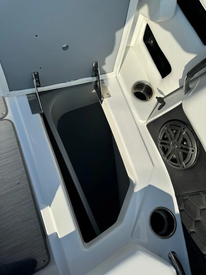 Slide: The Image of 2025 Four Winns H6 OB boat interior storage compartment with cup holders and speaker. - 27