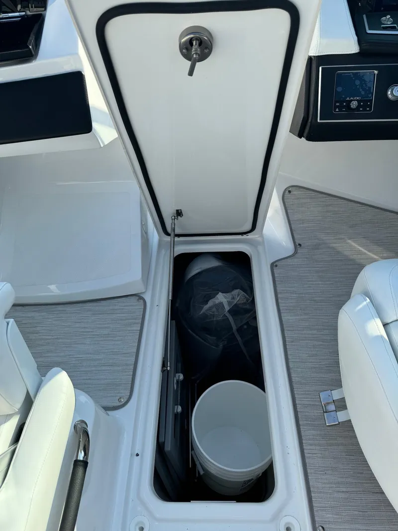 Slide: The Image of 2025 Four Winns H6 OB boat storage compartment with bucket and cover. - 28