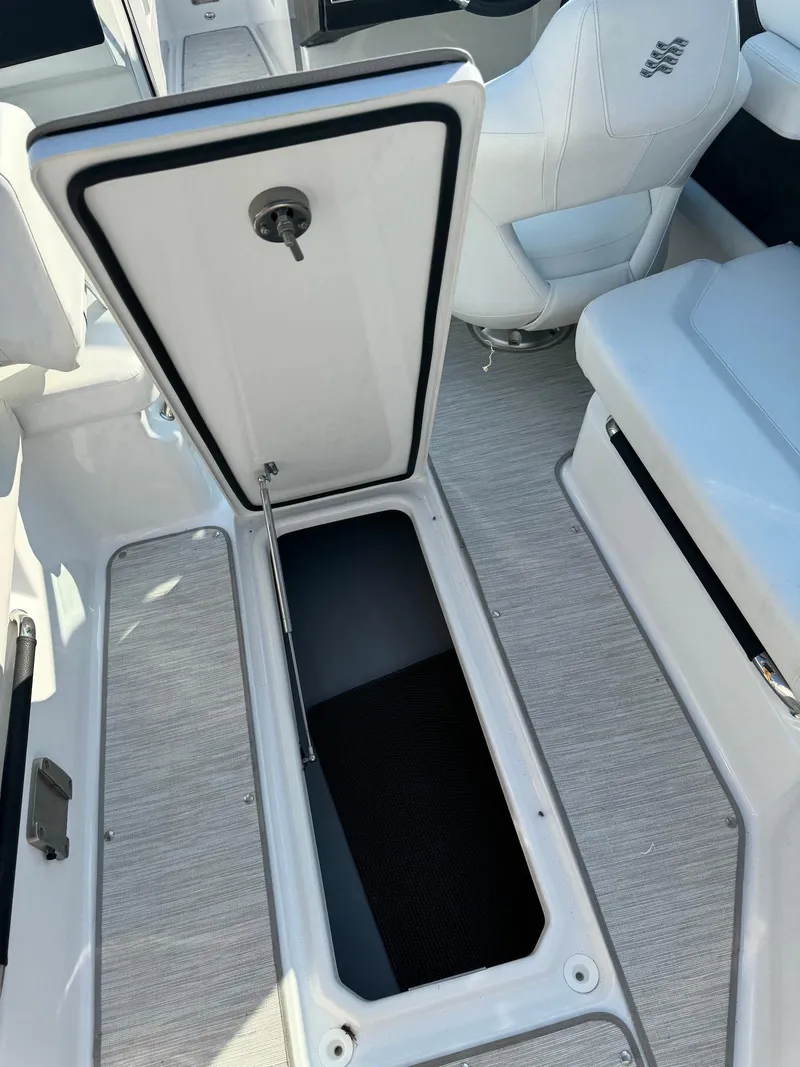 Slide: The Image of 2025 Four Winns H6 OB boat storage compartment with open hatch, white interior. - 29