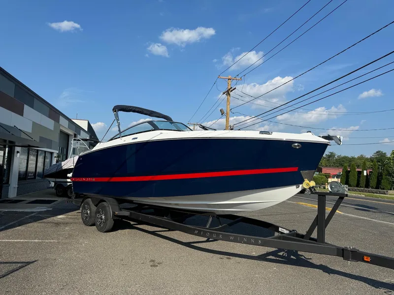 Slide: The Image of 2025 Four Winns H6 OB boat on trailer, parked outdoors under blue sky. - 3