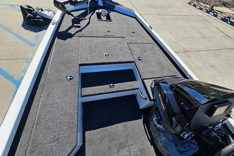 Slide: The Image of 2026 Vexus Defender 189 boat deck with motor, featuring carpeted surfaces and storage compartments. - 18