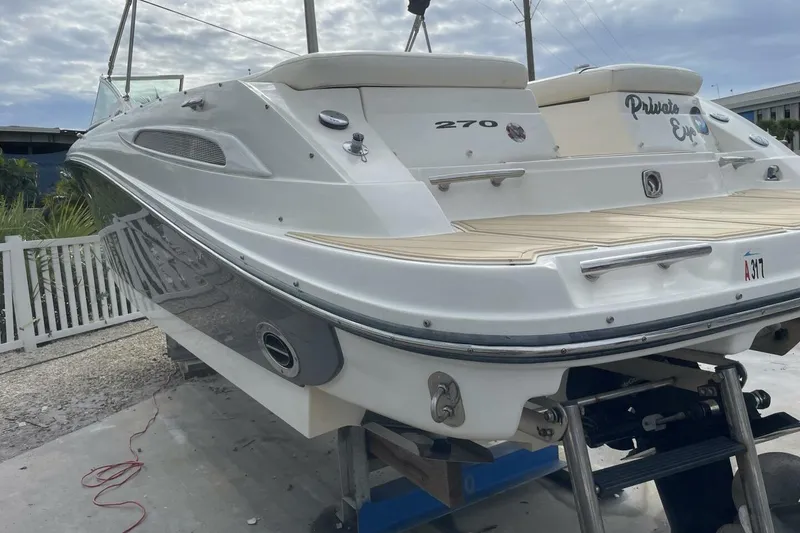 Slide: The Image of 2008 Sea Ray 270 SLX boat on a lift, showcasing sleek design and spacious deck. - 2