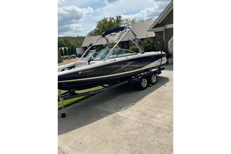 Slide: The Image of 2007 MasterCraft X-45 boat on trailer, parked in driveway, under cloudy sky. - 2