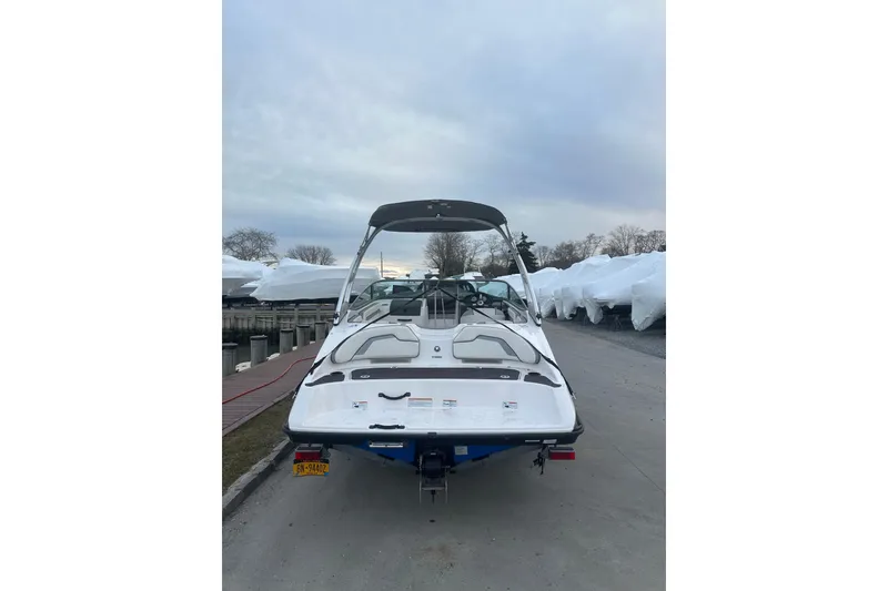 Slide: The Image of 2017 Yamaha Boats AR190, white, docked with covered boats in the background. - 4
