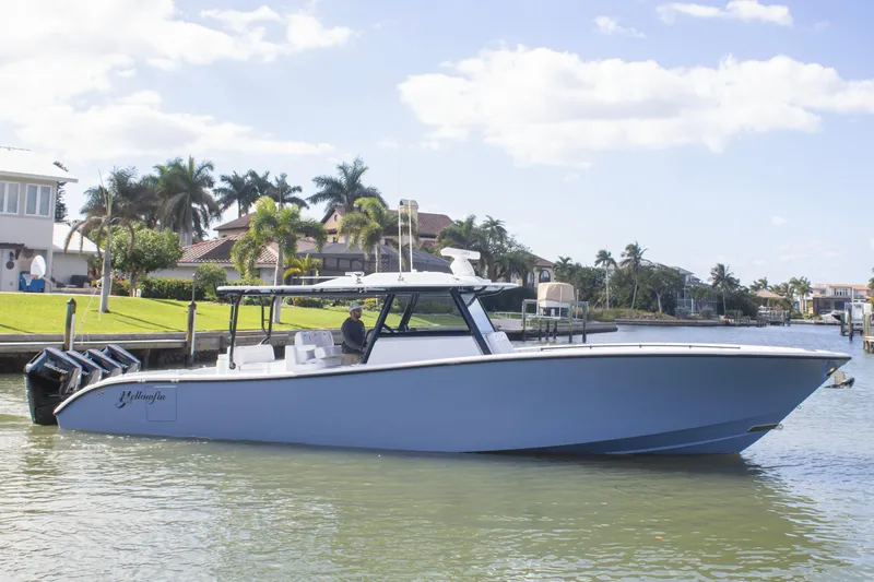 Slide: The Image of 2026 Yellowfin 42 Offshore boat cruising near waterfront homes and palm trees. - 1