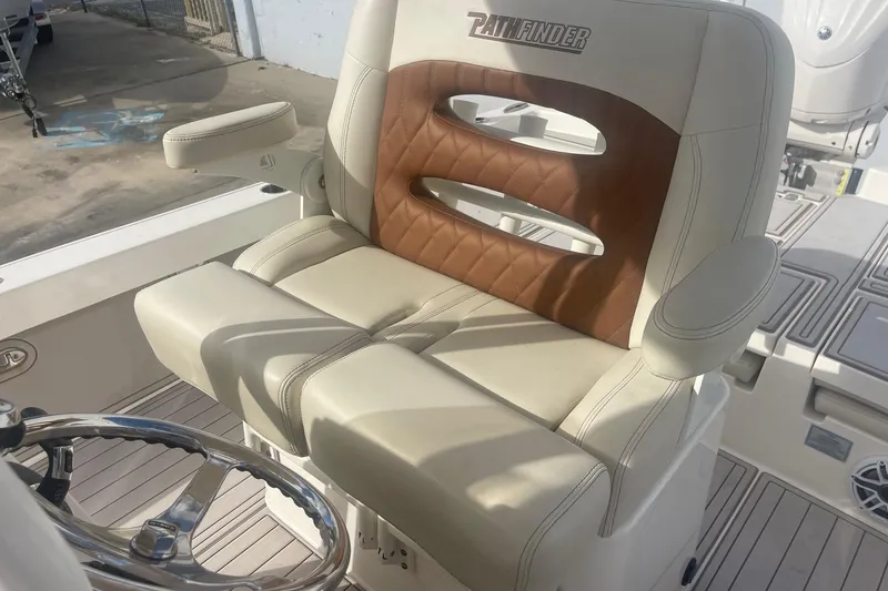 Slide: The Image of 2022 Pathfinder 2600 TRS boat seat with tan and brown upholstery, steering wheel visible. - 7