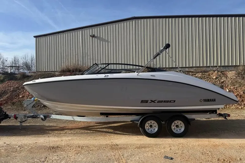 The Image of 2026 Yamaha Boats SX250 on trailer, parked outdoors near a metal building. - 0