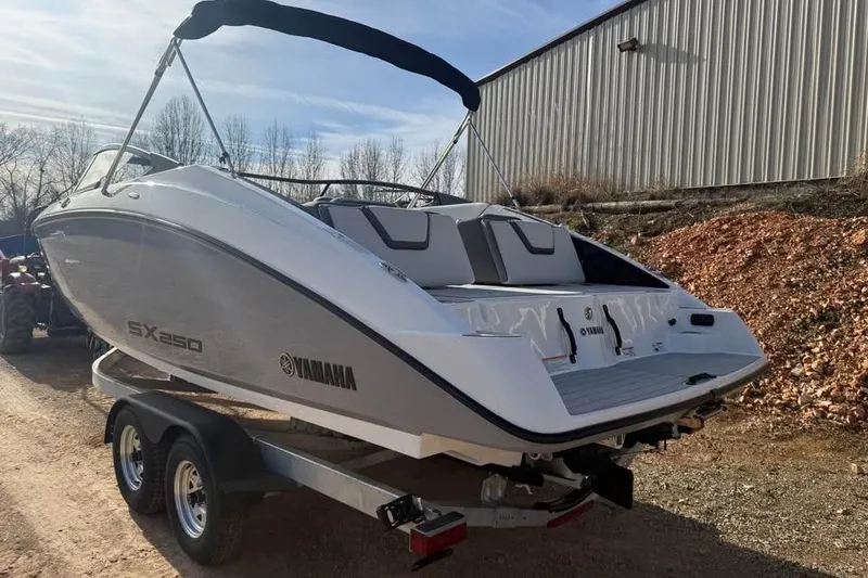 Slide: The Image of 2026 Yamaha Boats SX250 on trailer, parked outdoors near a metal building. - 6