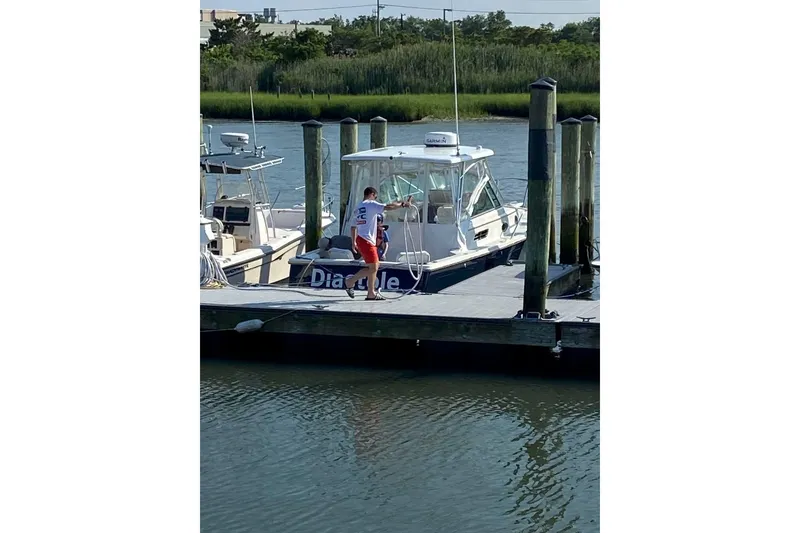 Slide: The Image of 2006 Back Cove 26 boat docked with person on pier, surrounded by water and greenery. - 10