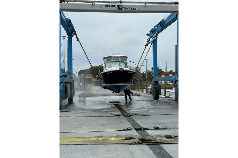 Slide: The Image of 2006 Back Cove 26 boat being lifted by a Marine Travelift at a dock. - 12