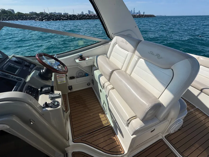 Slide: The Image of The image shows the cockpit of a 2011 Sea Ray Sundancer 330 with white leather seats and a wooden steering wheel. The sea is visible in the background. - 9