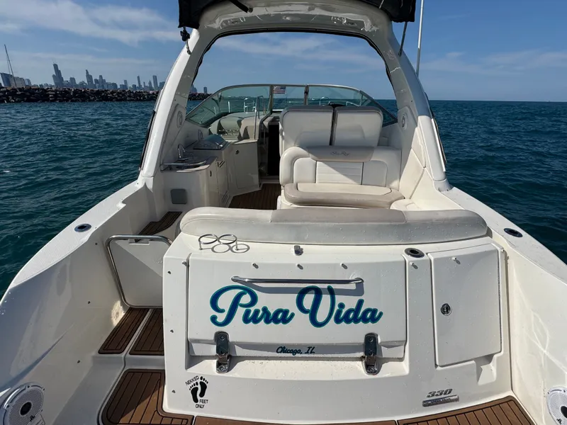 Slide: The Image of The image shows a 2011 Sea Ray Sundancer 330 on the water. "Pura Vida" is visible on the back, with a city skyline in the background. - 3