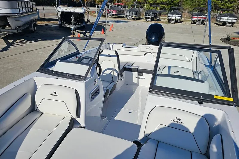 Slide: The Image of 2026 Stingray 172 DC boat interior with white seating and windshield, parked outdoors. - 11