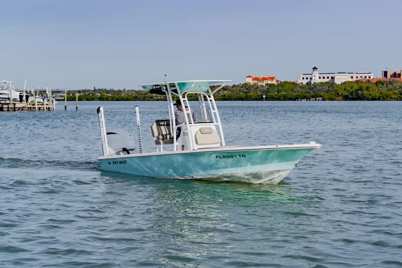 Slide: The Image of 2024 Key West 250 Bay Reef boat cruising on calm waters near a marina. - 10