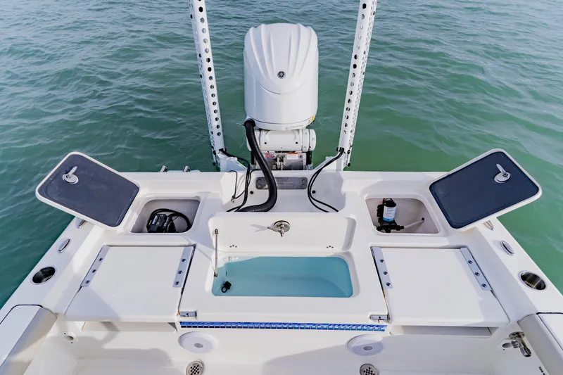 Slide: The Image of 2024 Key West 250 Bay Reef boat deck with storage compartments and motor, on water. - 30